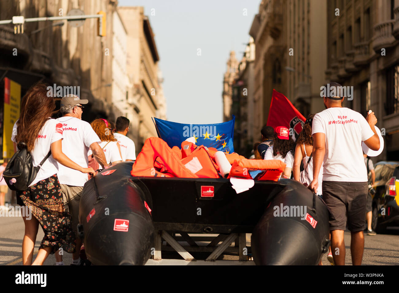 Barcelona, spain- 17 july 2019: young open arms activists march holding rubber dinghy and italian minister Salvini mask against immigration policies a Stock Photo