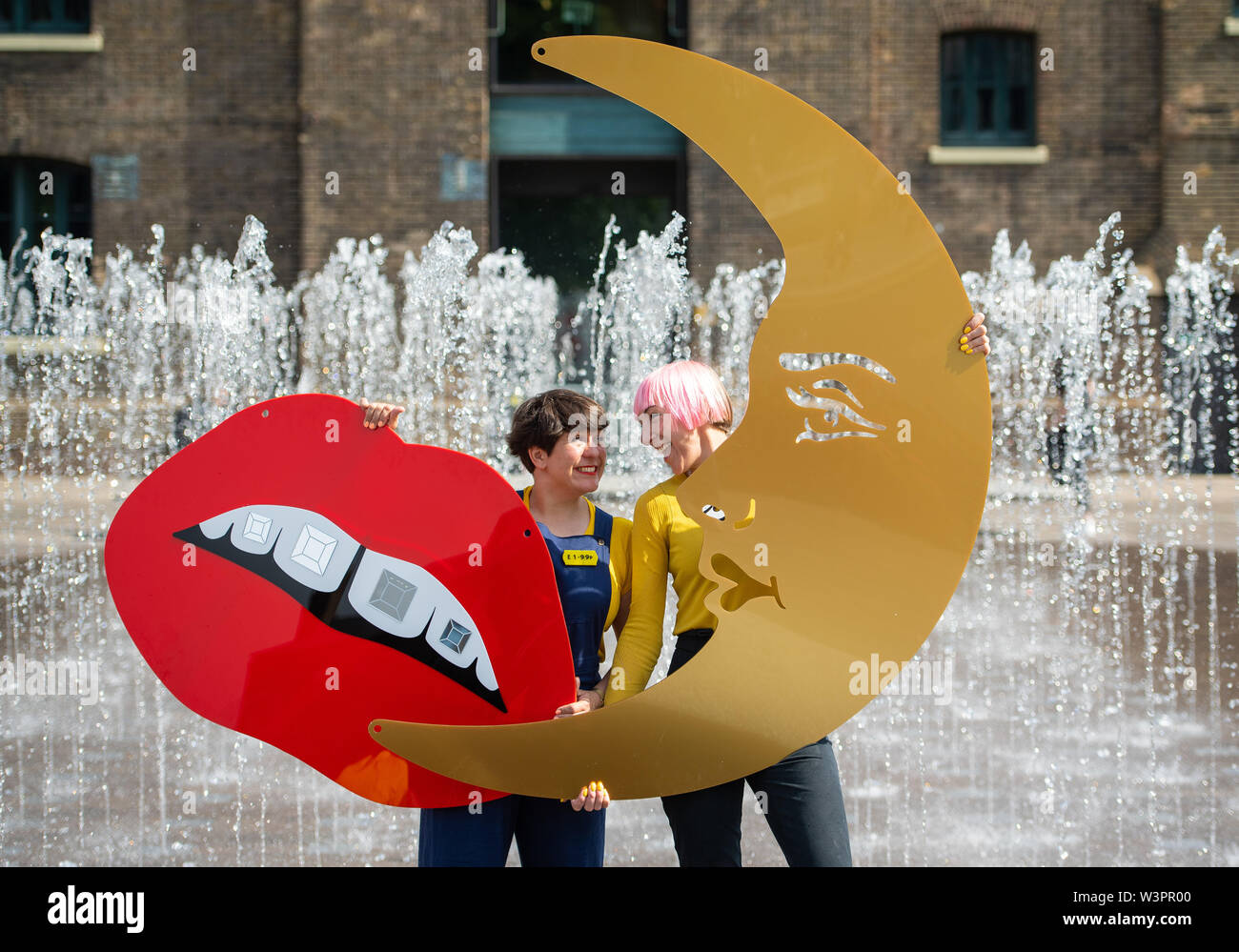 Tatty Devine founders Rosie Wolfenden (left) and Harriet Vine hold two of their designs, laser-cut acrylic lips and a crescent moon, part of the new Crafts Council exhibition 'Misshapes: the Making of Tatty Devine', which is at the Central Saint Martins' Lethaby Gallery in London, from July 20th until August 11th. Stock Photo