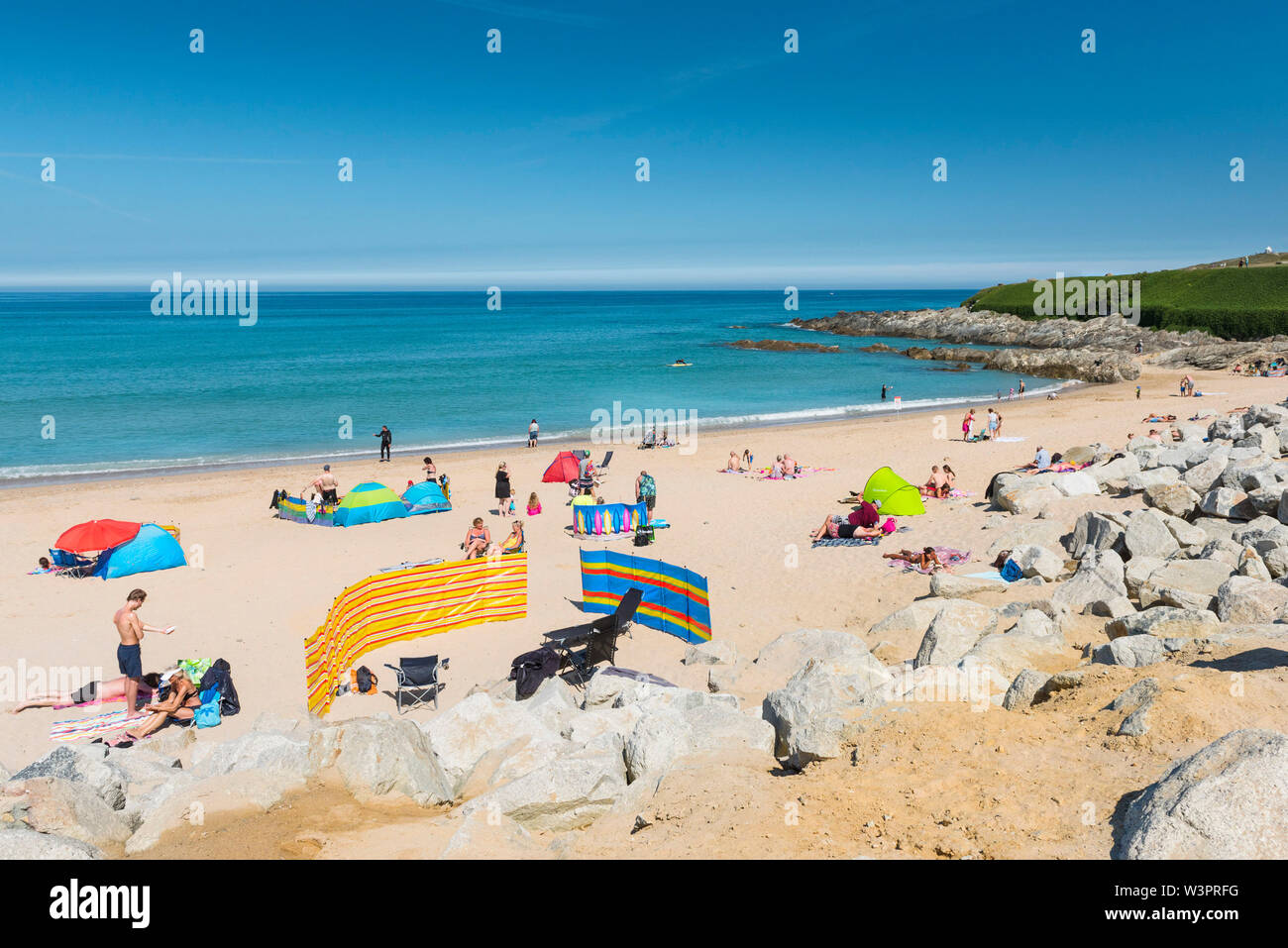Holidaymakers relaxing and enjoying the sunshine as they sunbathe on the beach at Fistral in Newquay in Cornwall. Stock Photo