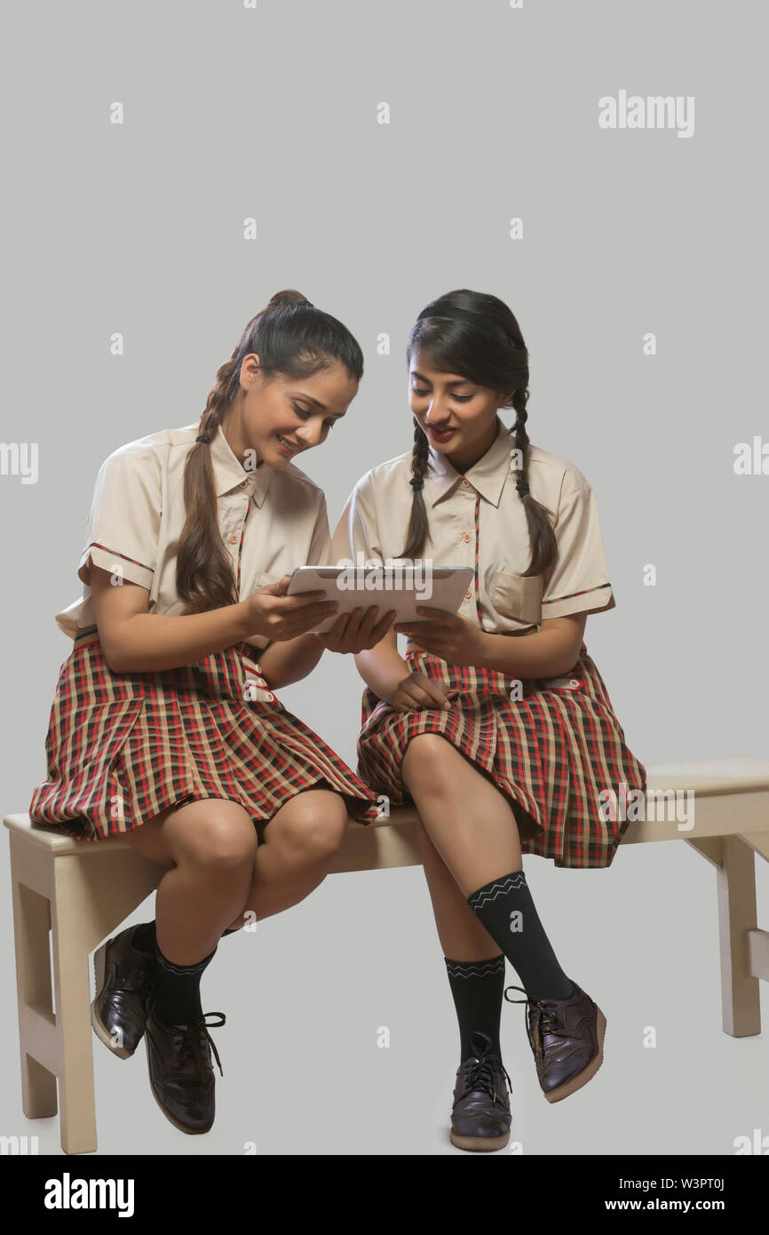 Two girls in school classroom studying from a digital tablet. Stock Photo