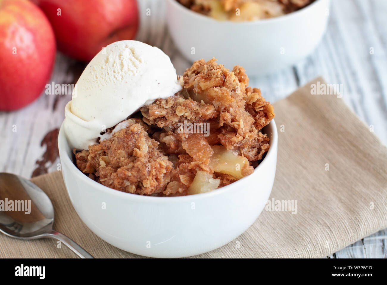 Fresh hot homemade apple crisp or crumble with crunchy streusel topping topped with vanilla bean ice cream. Selective focus with blurred background. Stock Photo