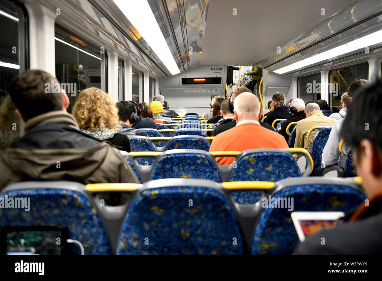 Commuters on a train, all leaving a seat between themselves and the next person, thereby avoiding sitting next to strangers. Sydney, Australia Stock Photo