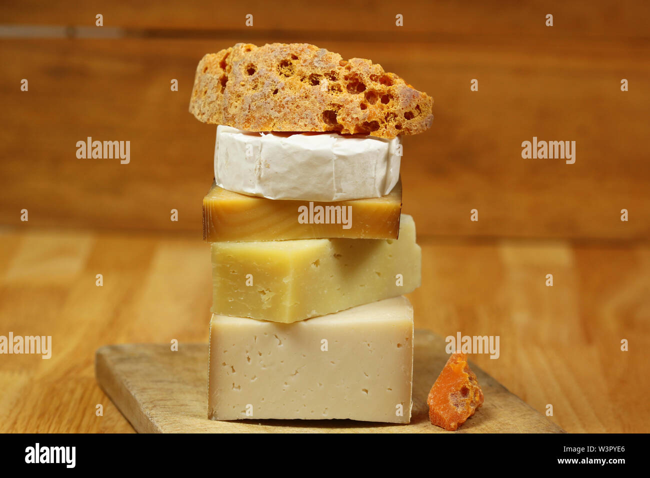 Stack of different kinds of cheese on wooden board - goat cheese, mimolette and camembert Stock Photo