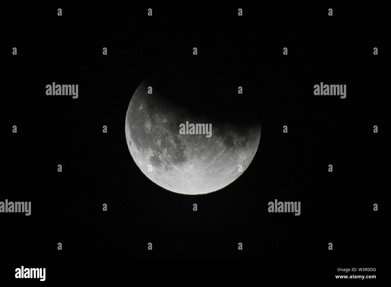 close up view of a partial lunar eclipse in the black night sky in July ...