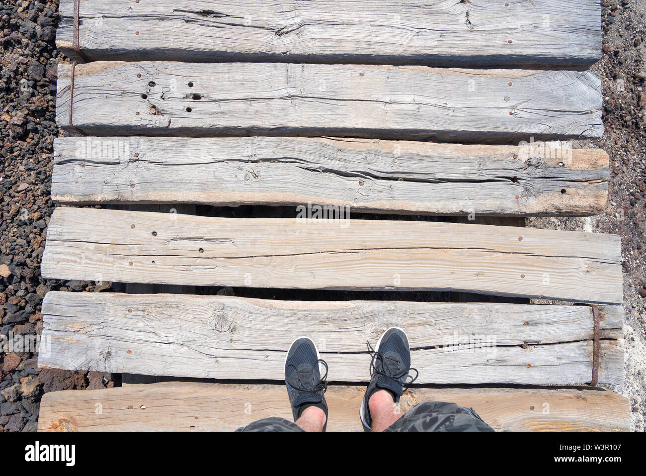Feet in sneakers on a wooden walkway. The concept of the wooden walkway ...