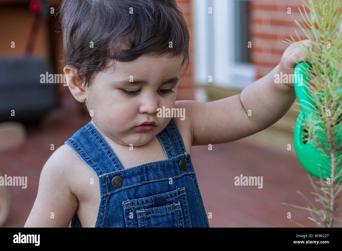 Cute little gardener in a garden of a house with a small green watering