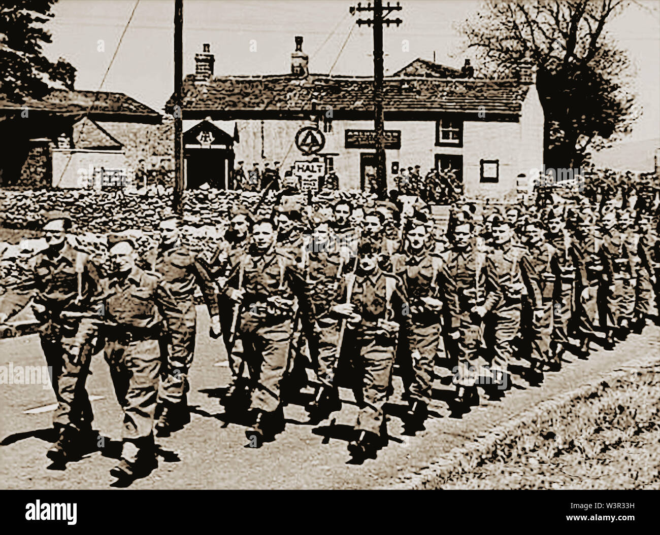 A news picture taken in WWII of the local Home Guard marching past the Anchor Inn at Tideswell village  near Buxton, in the Peak District of Derbyshire, UK. (Note the AA telephone box) Stock Photo