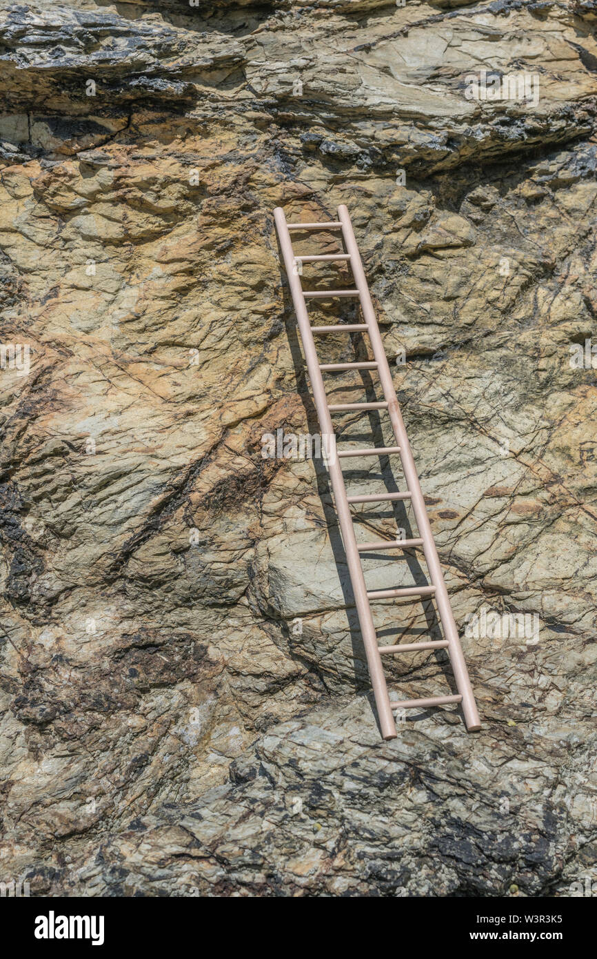 Small wood toy ladder propped against cliff face. Metaphor climbing