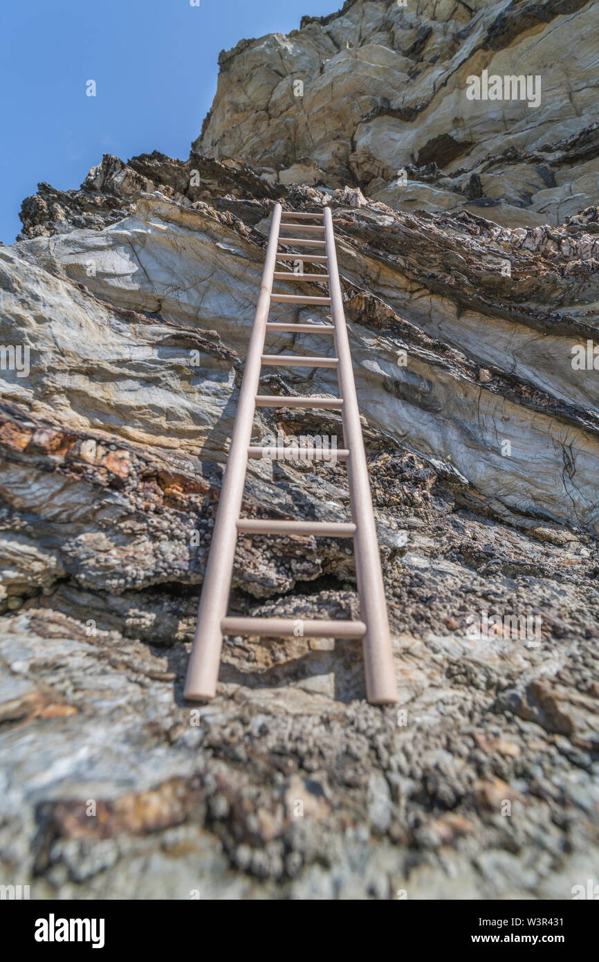 Small wood toy ladder propped against cliff face. Metaphor climbing