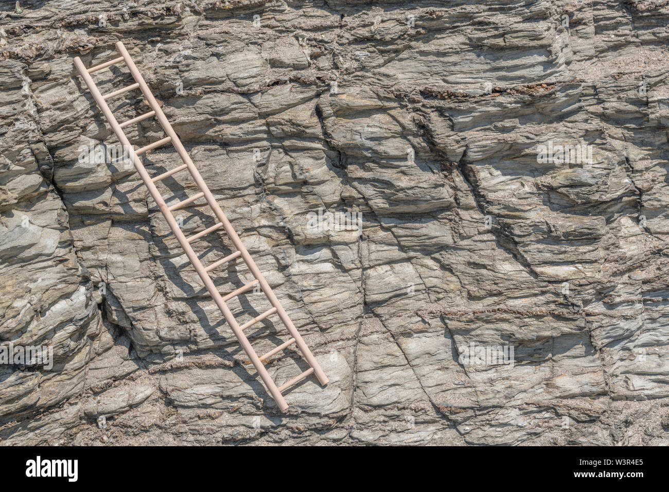 Small wood toy ladder propped against cliff face. Metaphor climbing
