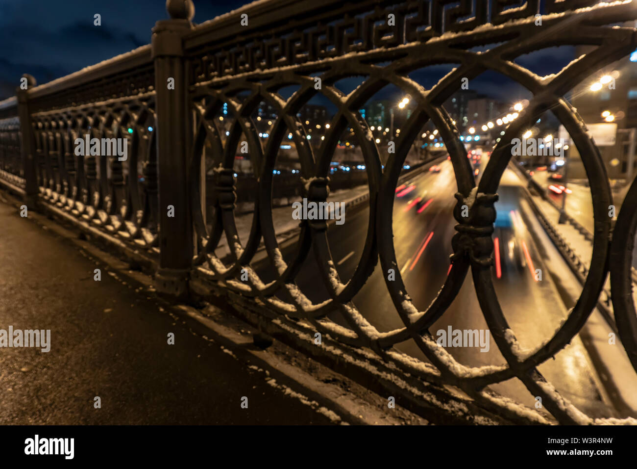 shot of the night traffic made through a cast-iron fence Stock Photo