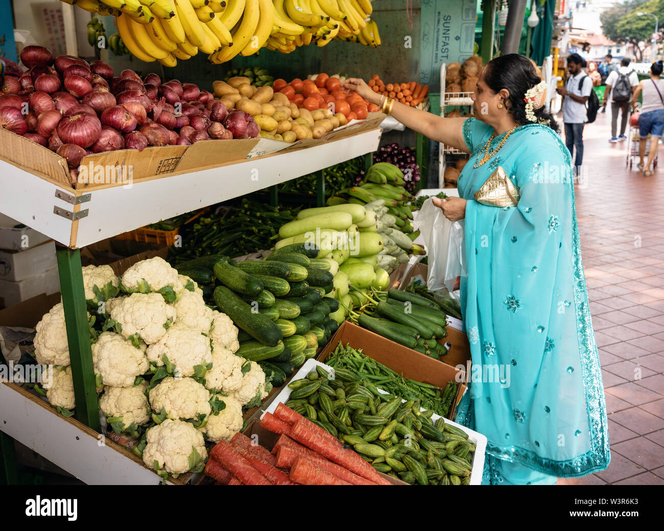 Chinatown, Singapore - February 9, 2019: Indian woman in saree buys fruits and vegetables at the market in Little India, Singapore Stock Photo