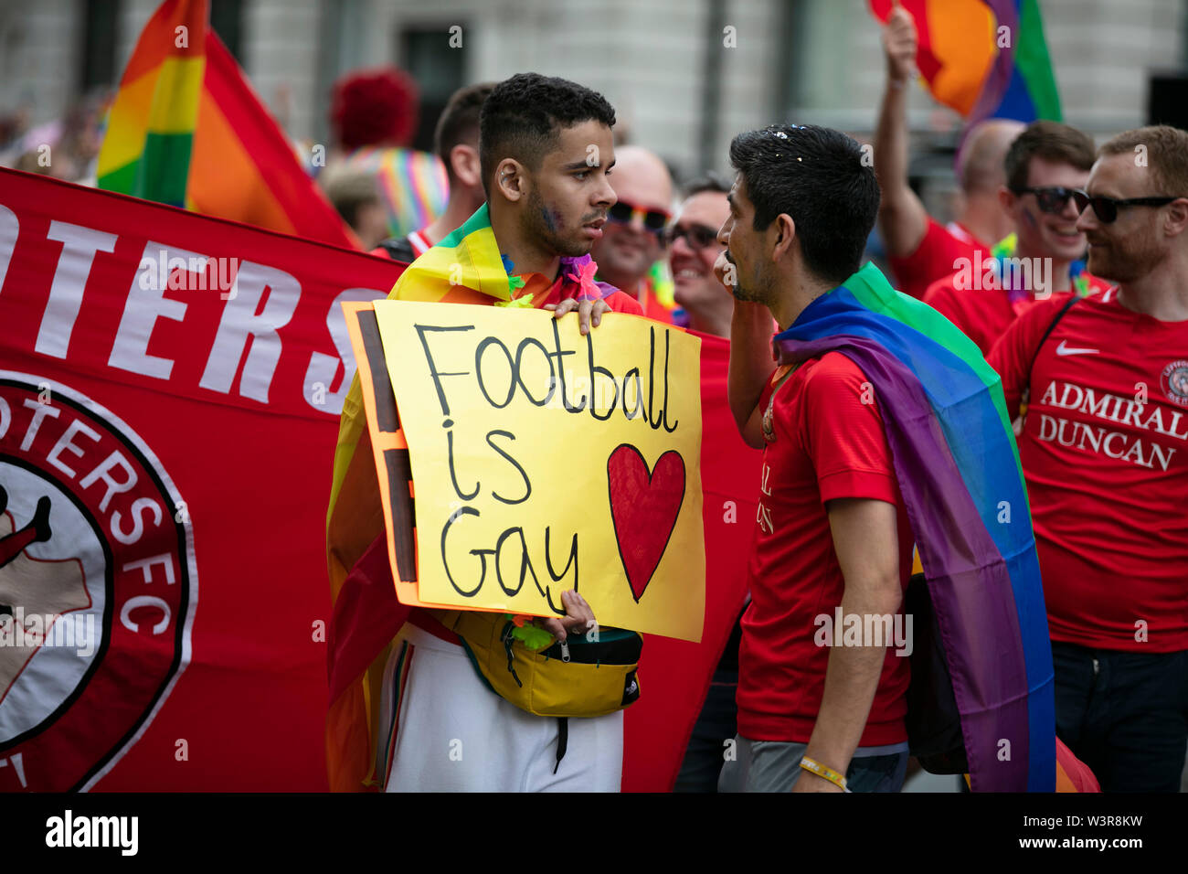 LONDON, UK - July 6th 2019: A man holds a football is gay banner at the annual gay pride march in central London Stock Photo