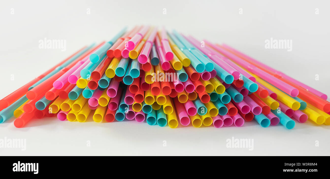 Colorful singleuse plastic drinking straws spread on a white