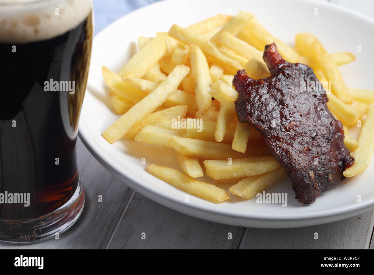 Grilled pork ribs with French fries and a glass of dark beer Stock Photo