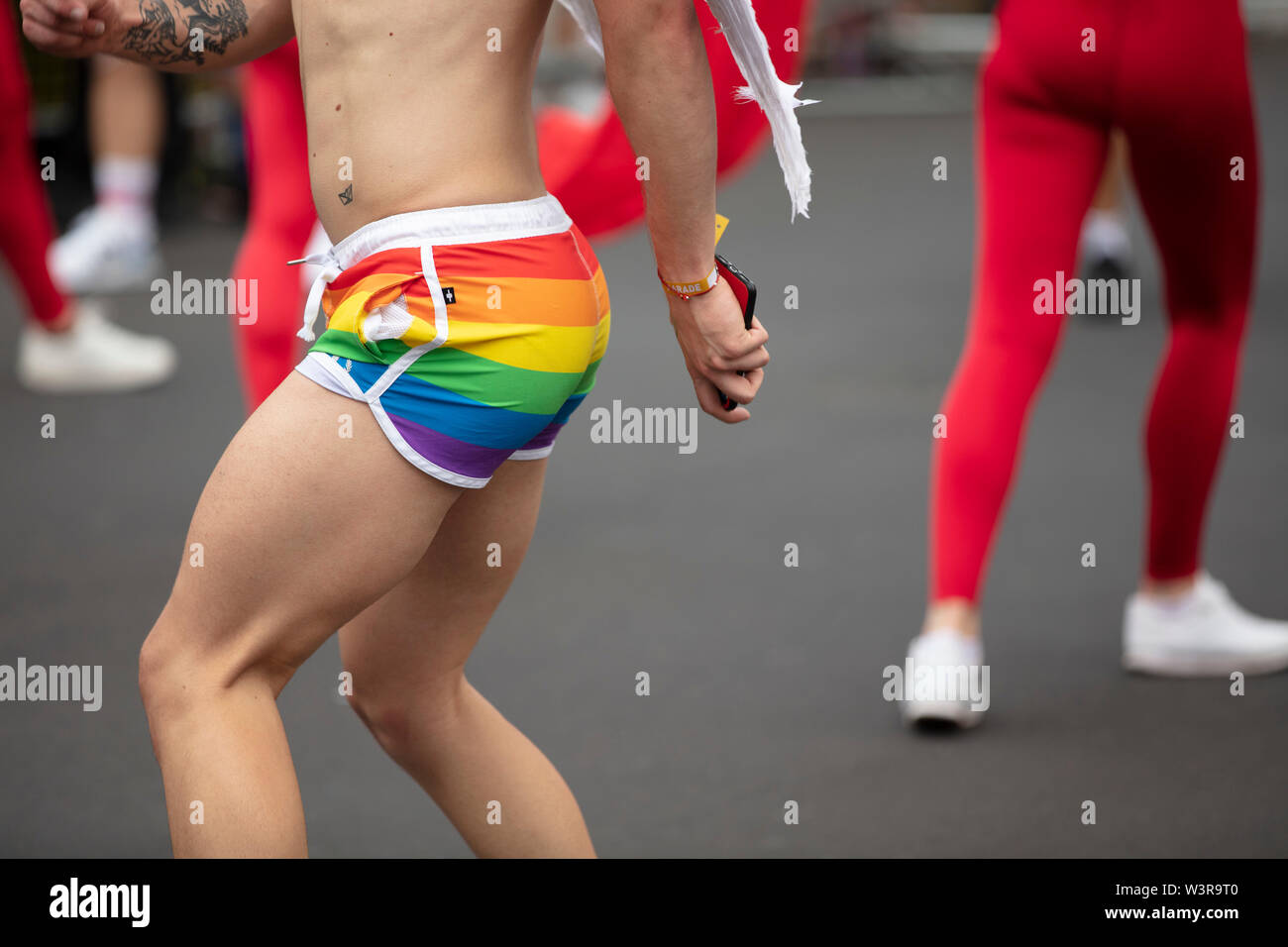A man wearing gay pride flag shorts dancing in the street at a pride event  Stock Photo - Alamy