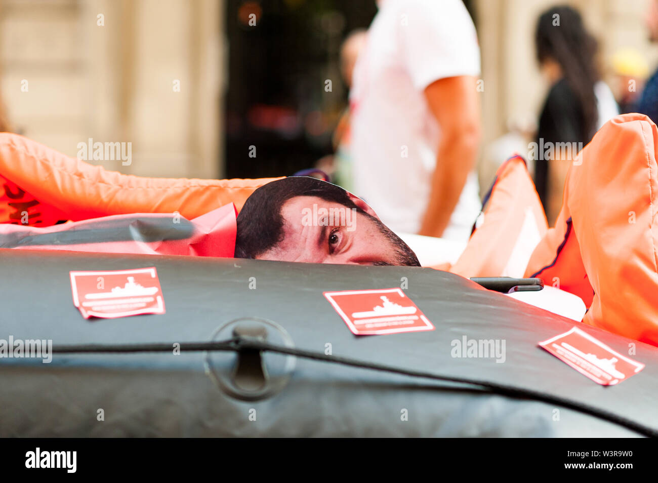 Barcelona, spain- 17 july 2019: mask of salvini face  drowning inside rubber dinghy with life belts and proactiva open arms stickers as a symbol of mi Stock Photo