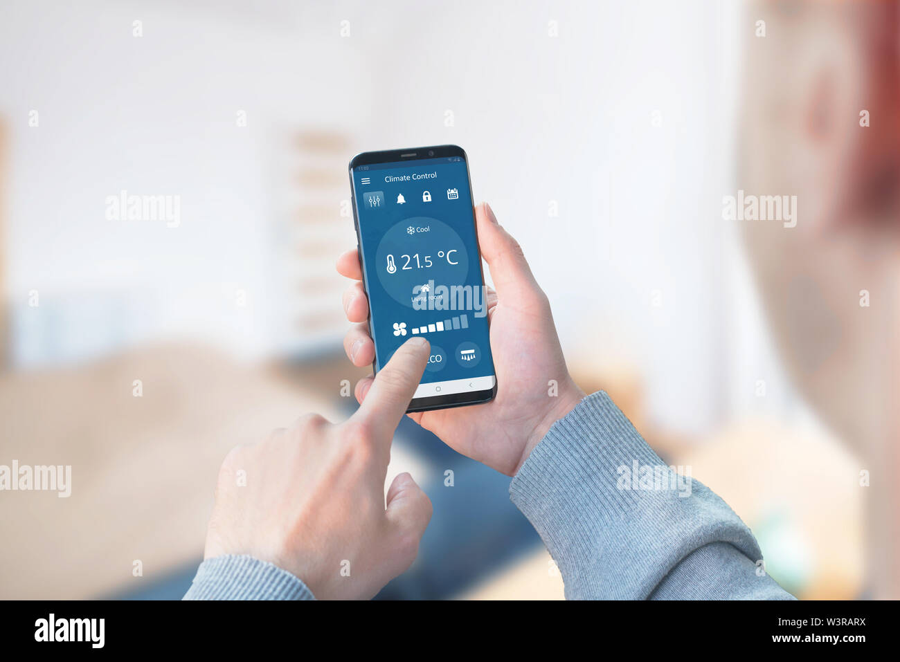 Man use the app to control the climate in the living room. Concept of a modern app with wi-fi control climate devices. Stock Photo