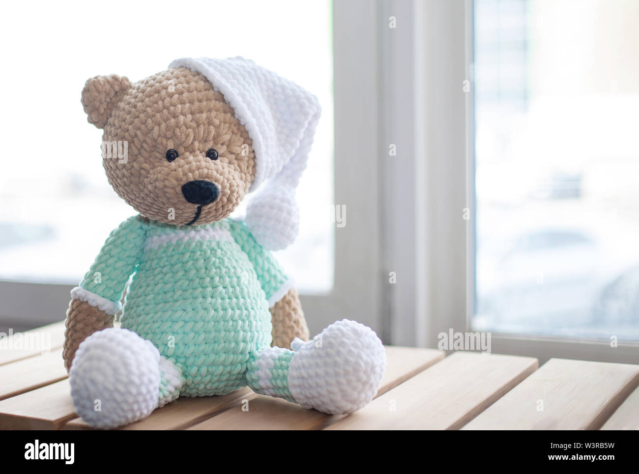 Handmade amigurumi teddy bear on wooden table. Stock Photo