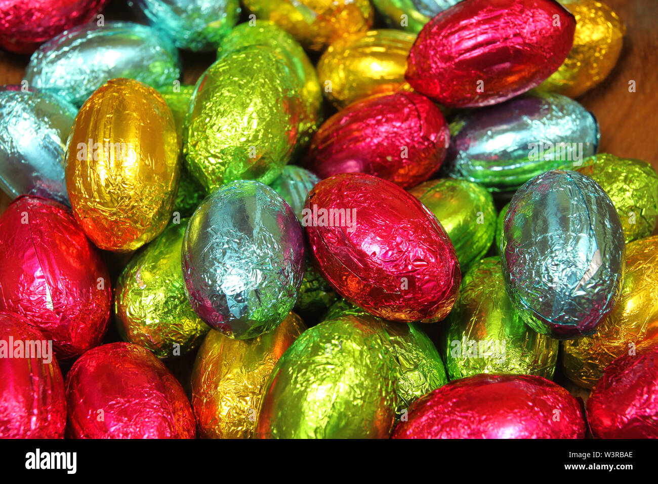 Stack of chocolate eggs in multi colored foils. Easter sweets Stock Photo