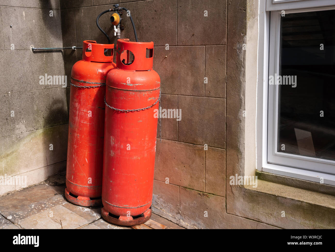 Two Red Propane Cylinder on the exterior of an old house Stock Photo
