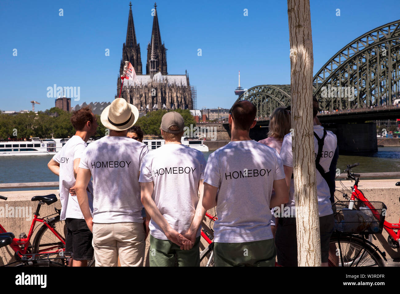 men in Homeboy t-shirts looking towards the cathedral and the Hohenzollern bridge, Cologne, Germany.  Maenner mit Homeboy T-Shirts schauen zum Dom und Stock Photo