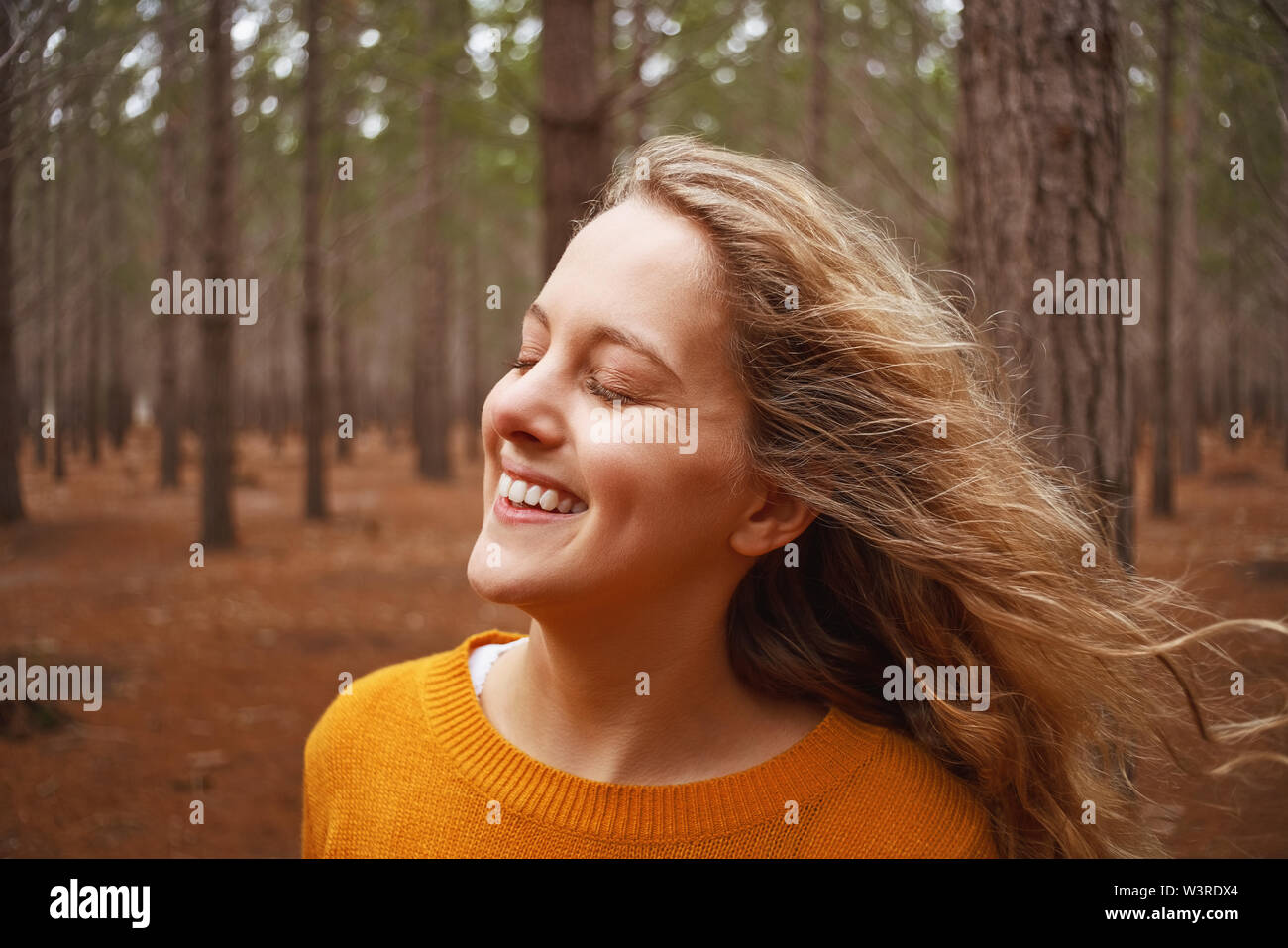 Smiling young woman enjoying the fresh air in the forest Stock Photo