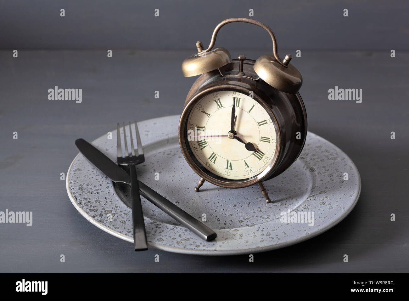 concept of intermittent fasting, ketogenic diet, weight loss. alarmclock fork and knife on a plate Stock Photo