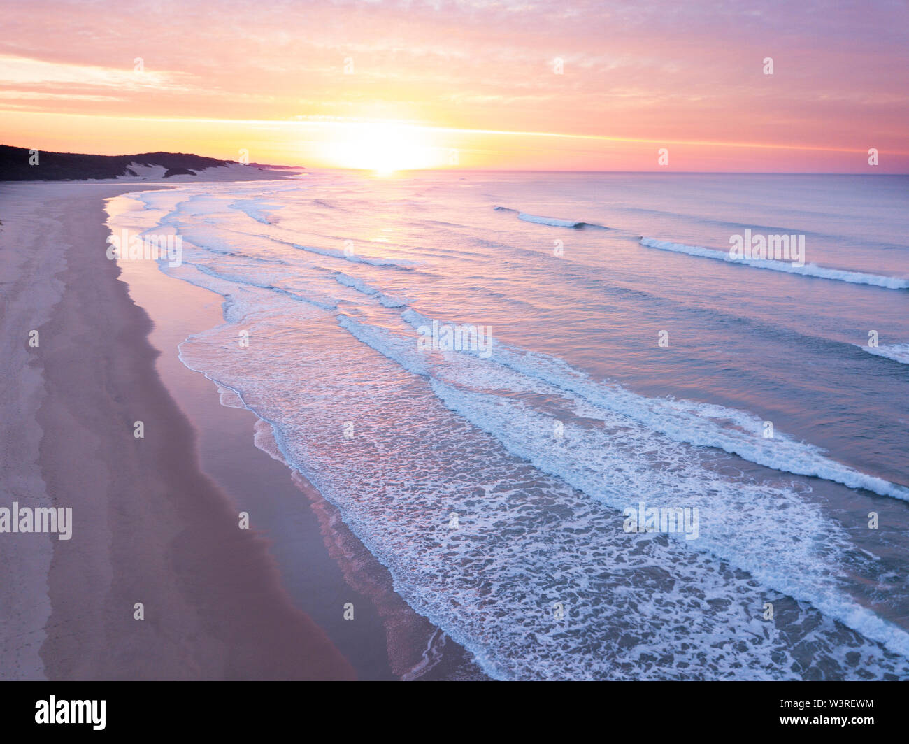 Aerial view over a wide open ocean and beach at sunrise Stock Photo