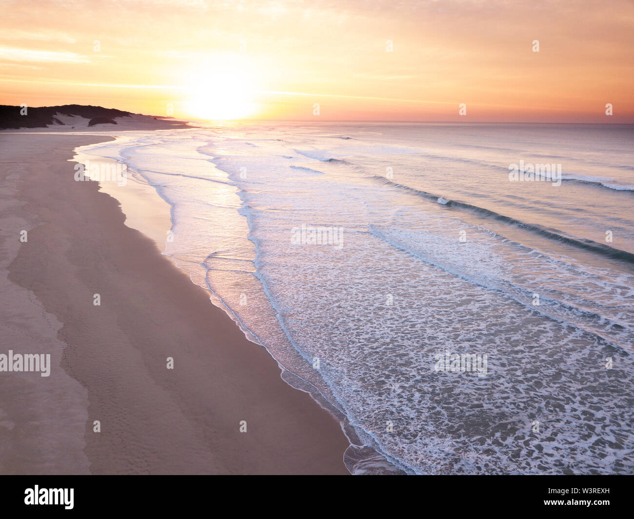 Aerial view over a wide open ocean and beach at sunrise Stock Photo