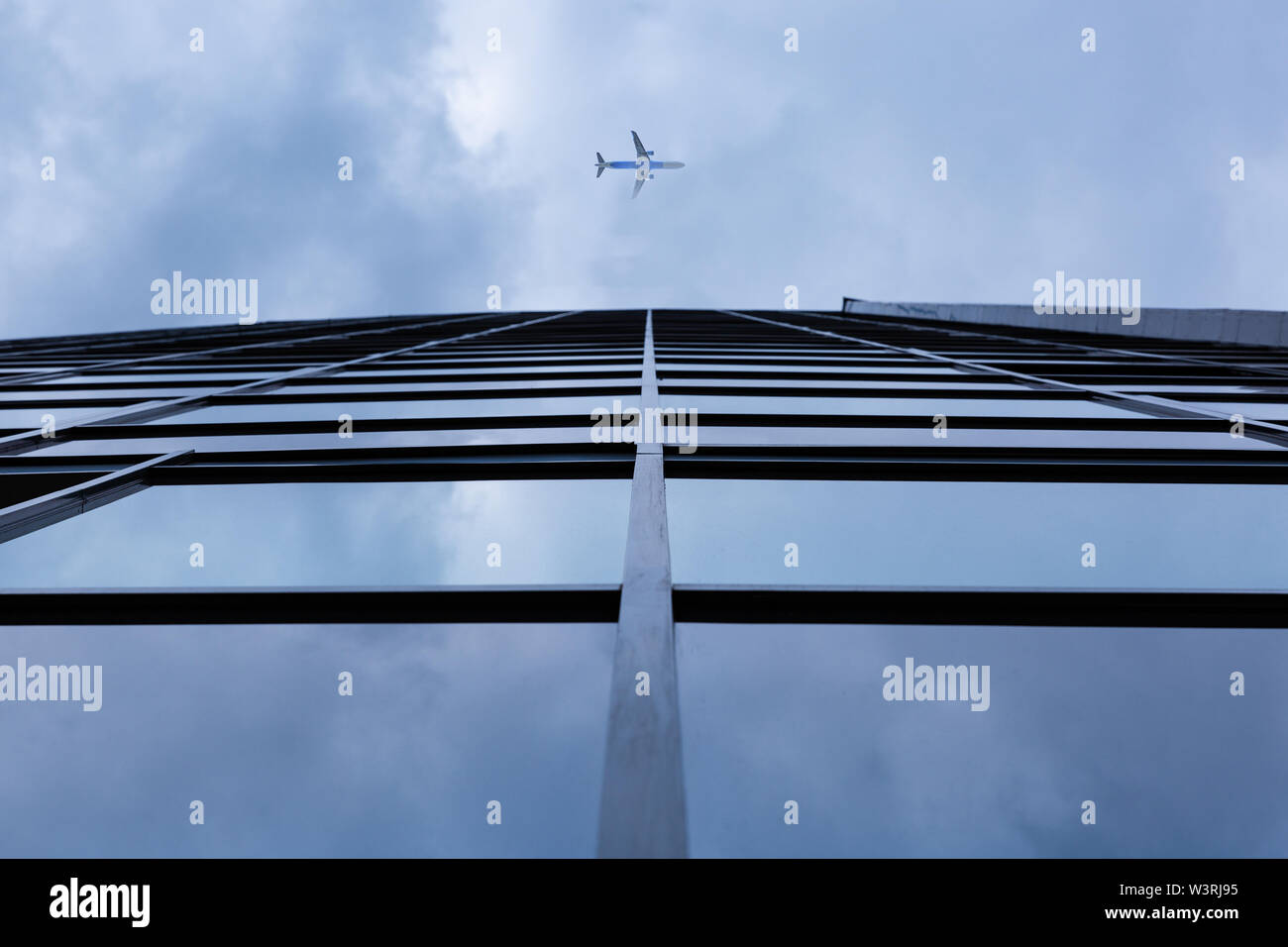 Airplane flying above modern architecture glass office building Stock Photo