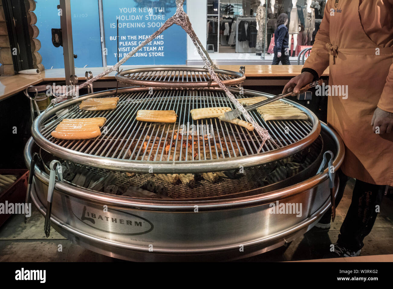 Large round barbecue with bratwurst sausages grilling on the griddle in