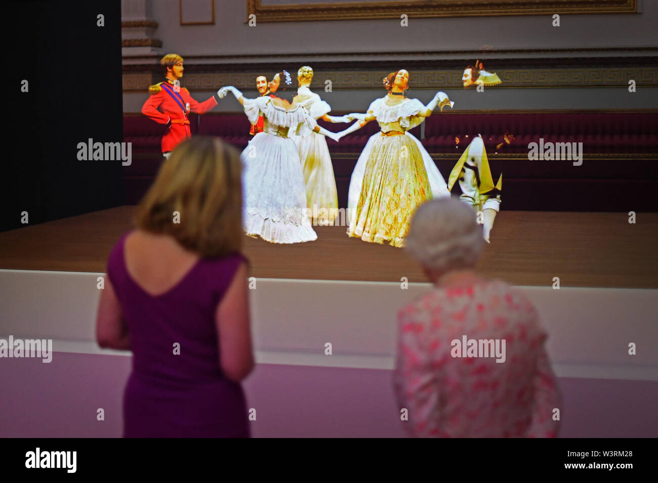 Queen Elizabeth II looks at a Victorian illusion technique known as Pepper's Ghost of a waltz danced at the Crimean Ball of 1856, in the Ballroom at Buckingham Palace, as part of the exhibition to mark the 200th anniversary of the birth of Queen Victoria for the Summer Opening of Buckingham Palace, London. Stock Photo