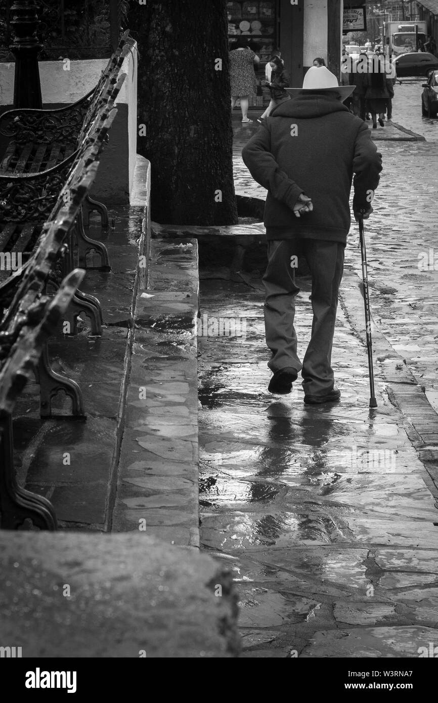 Old man wise walking on the wet road Stock Photo