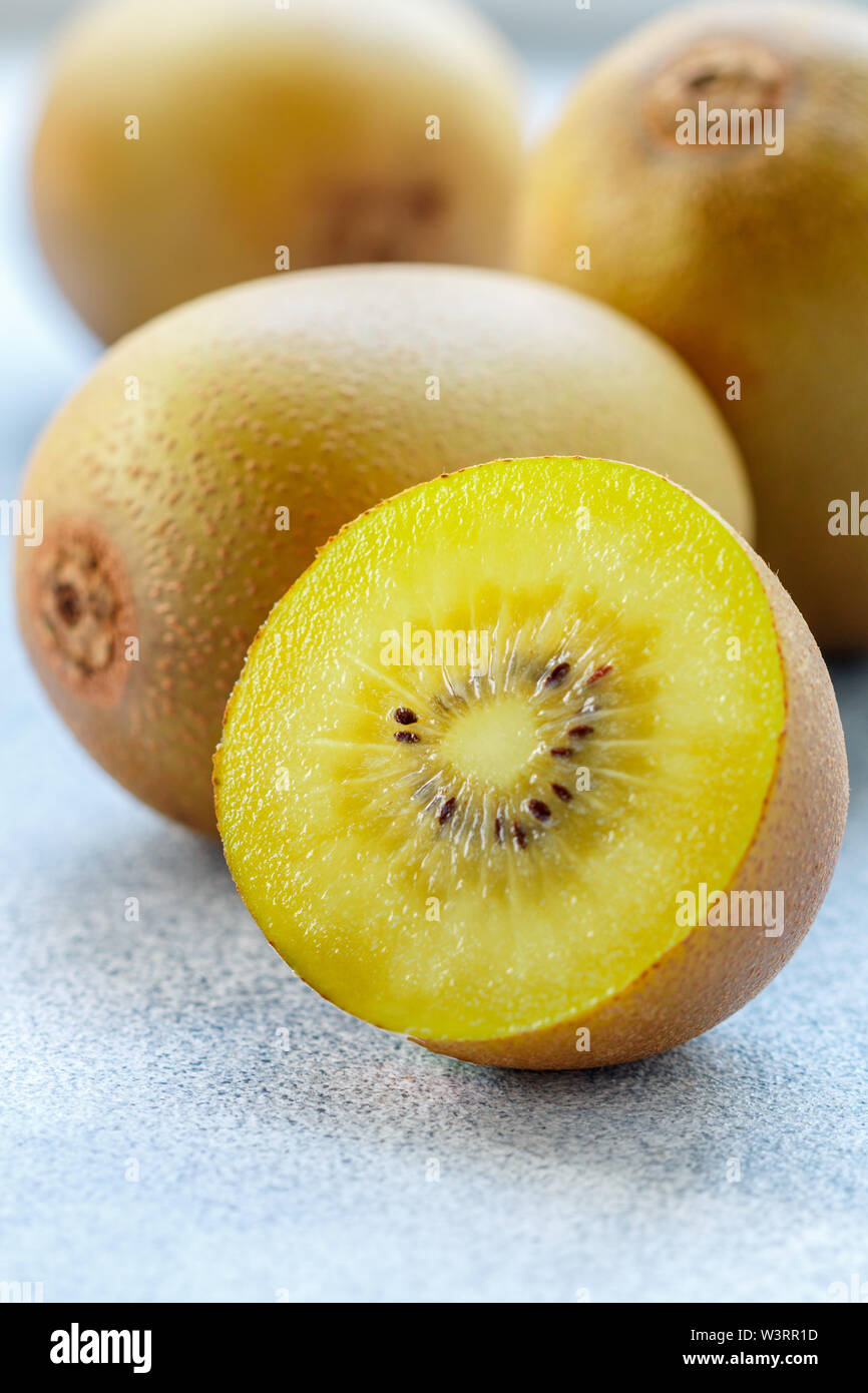 Golden (yellow) organic kiwi. Whole and cut ripe juicy fruits on grey