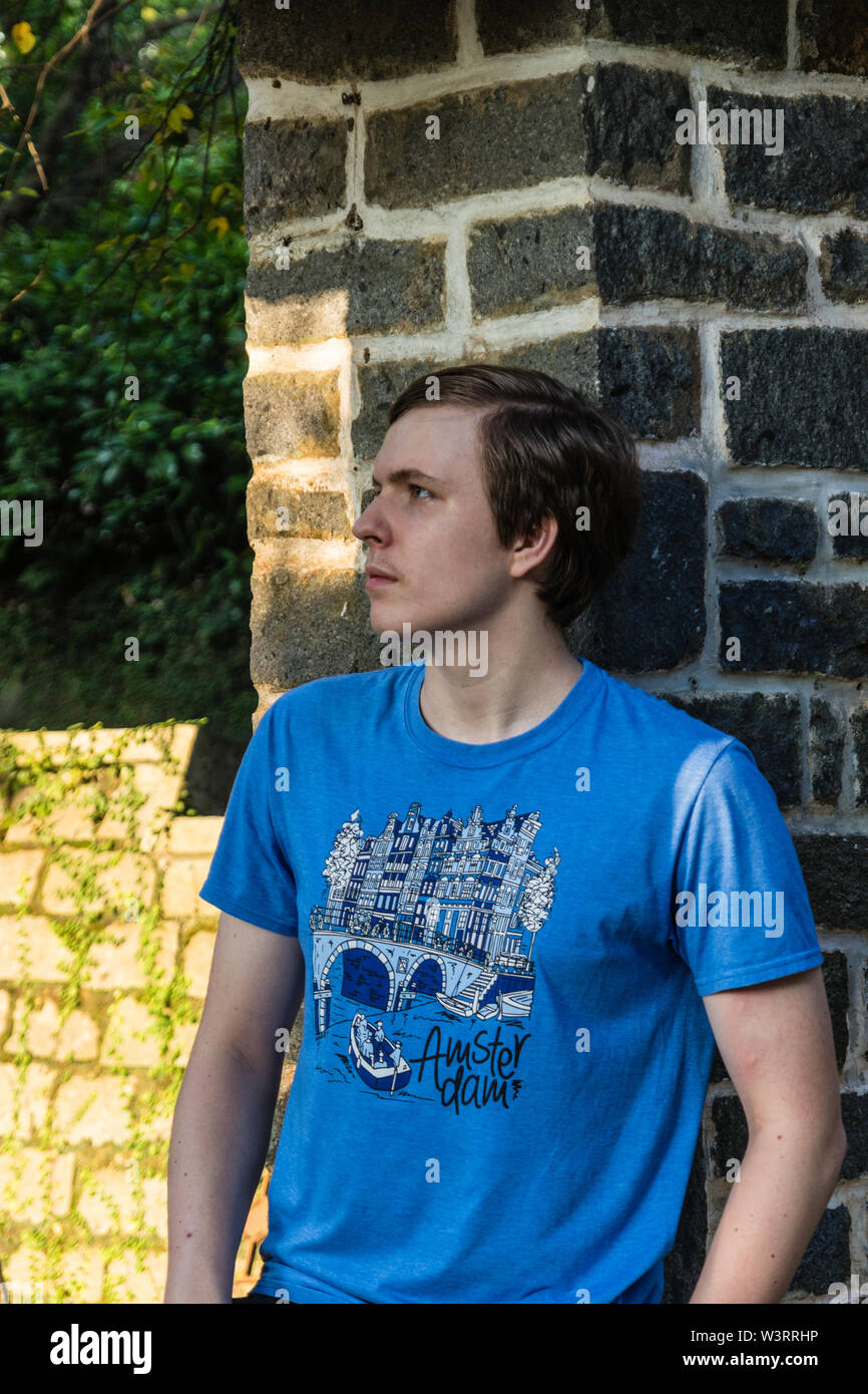 A handsome teenager leaning on the wall and dreaming Stock Photo