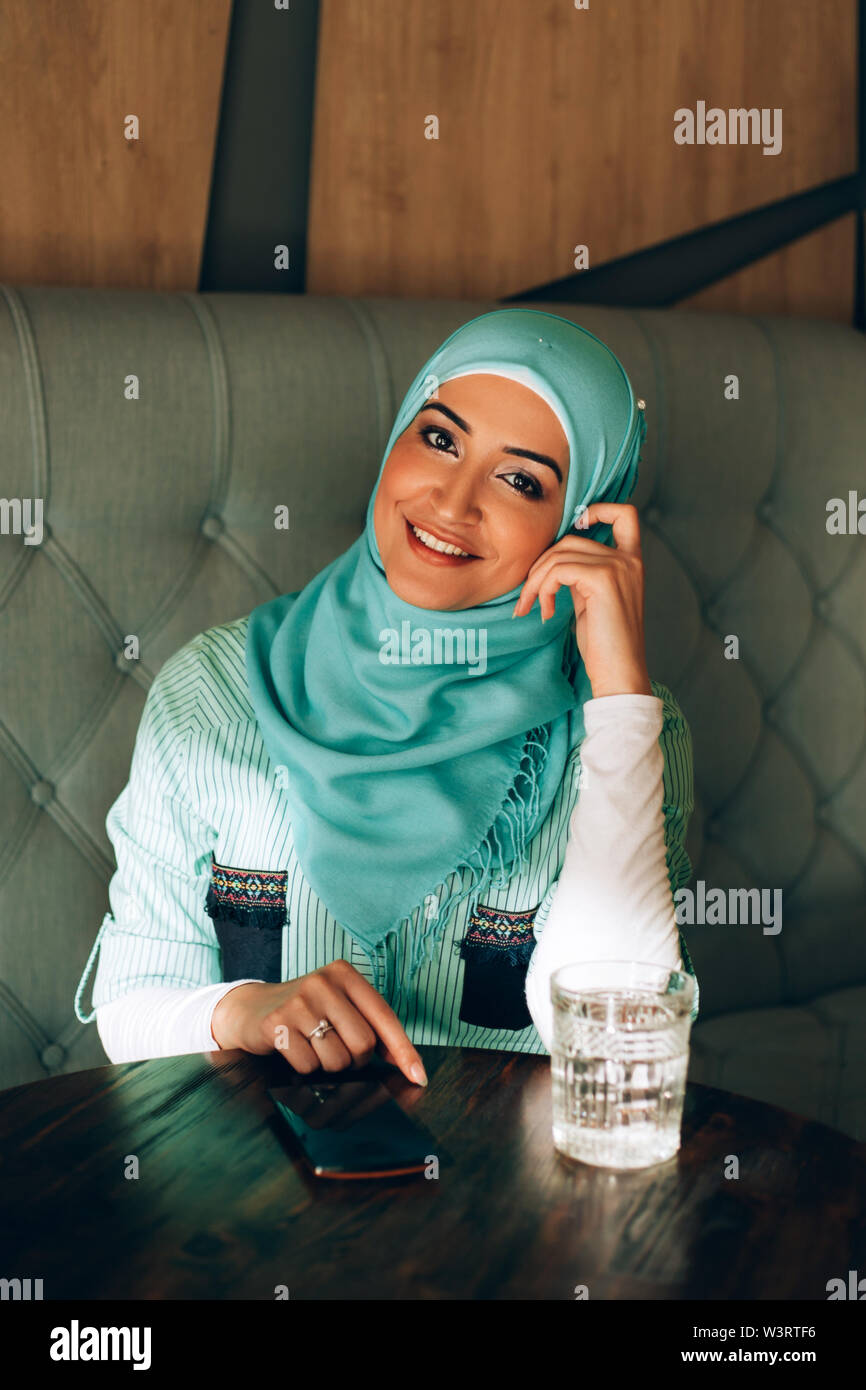 Beautiful young arabic girl in hijab using phone at cafe Stock Photo - Alamy