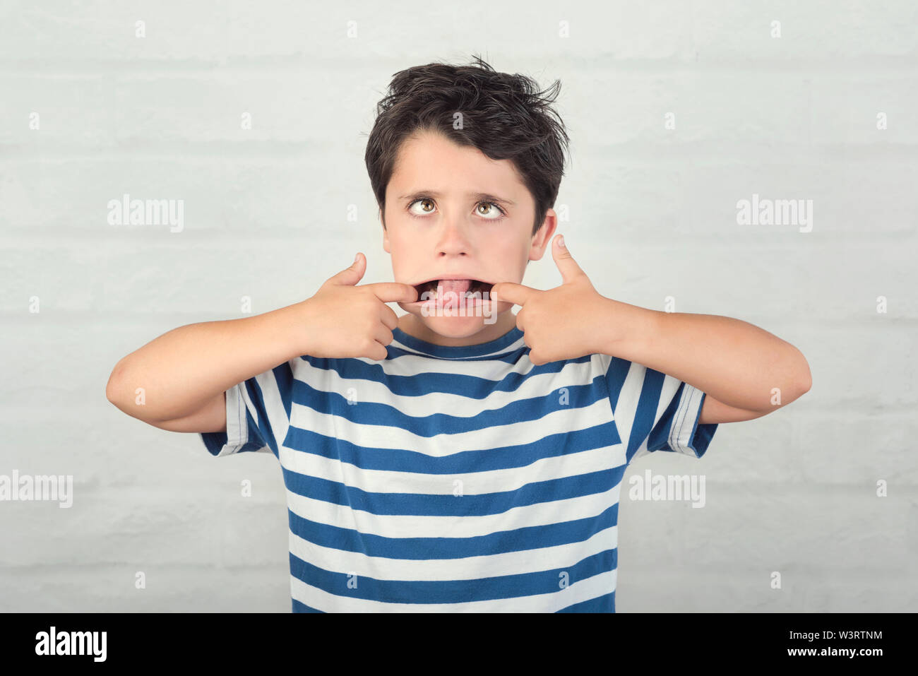 rude child making a grimace against brick background Stock Photo