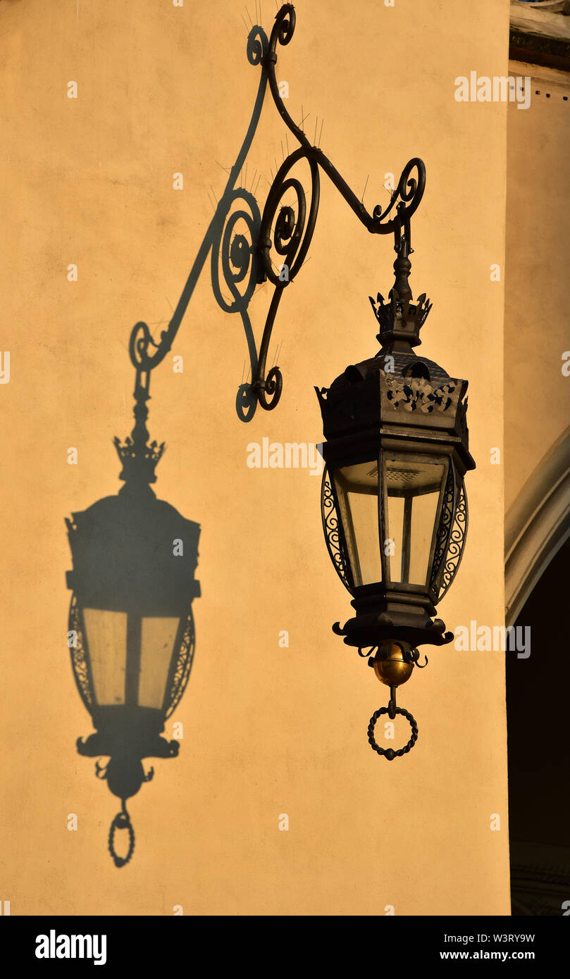Ornate wrought-iron lamp casts a shadow onto the beautiful Cloth Hall, Krakow, Poland, Europe. Stock Photo
