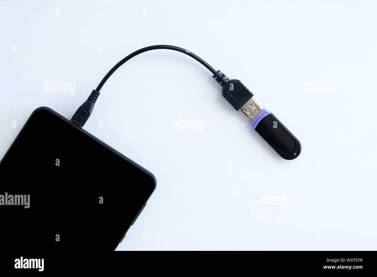 Transfer digital data. The cable is connected to the smartphone and USB flash drive. White background. Stock Photo