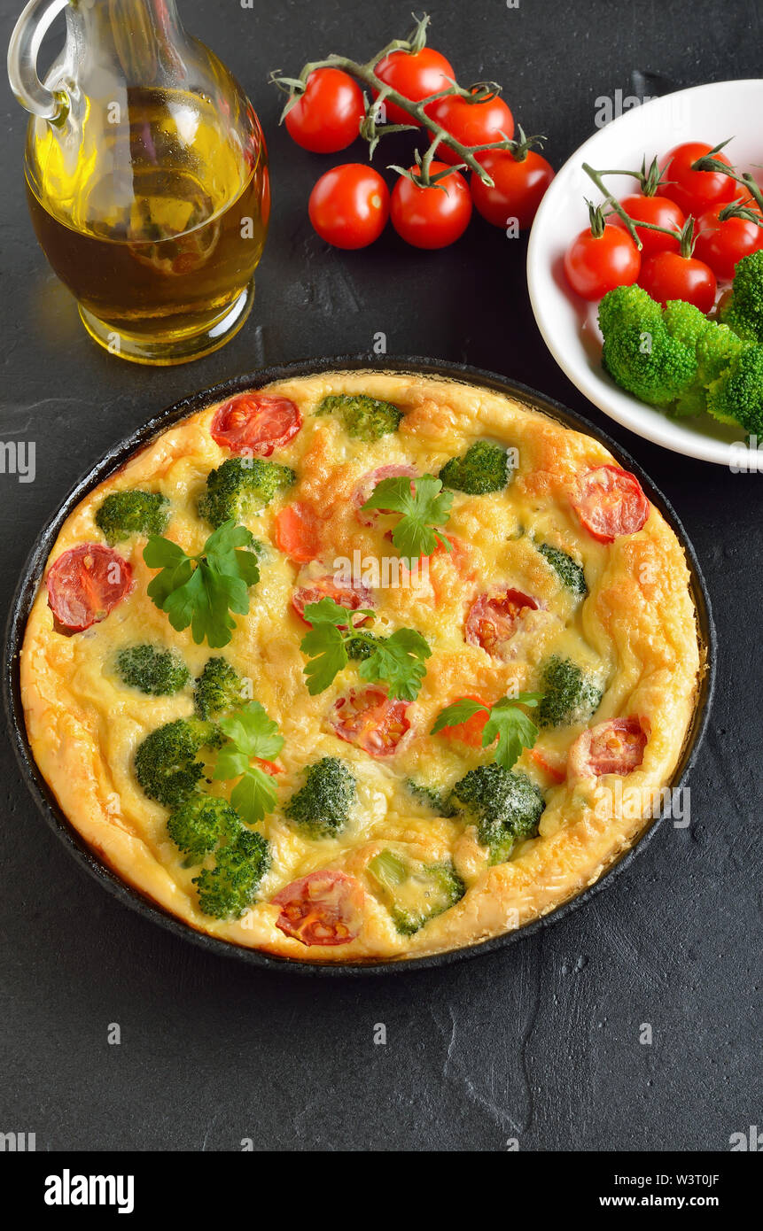 Frittata with broccoli and tomatoes in frying pan Stock Photo