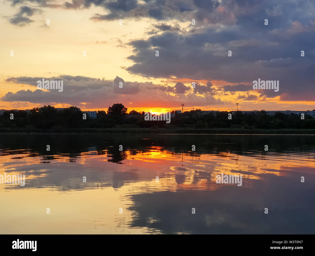 Beautiful sunset over the city horizon with reflection on the calm lake ...