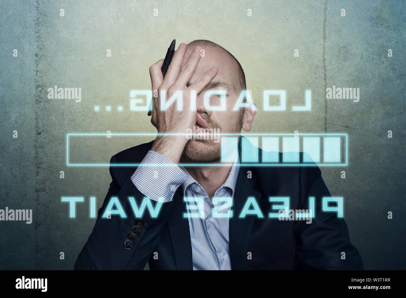 businessman or office worker waits bored and long on his slow computer or internet connection, displaying a loading bar and a message Stock Photo