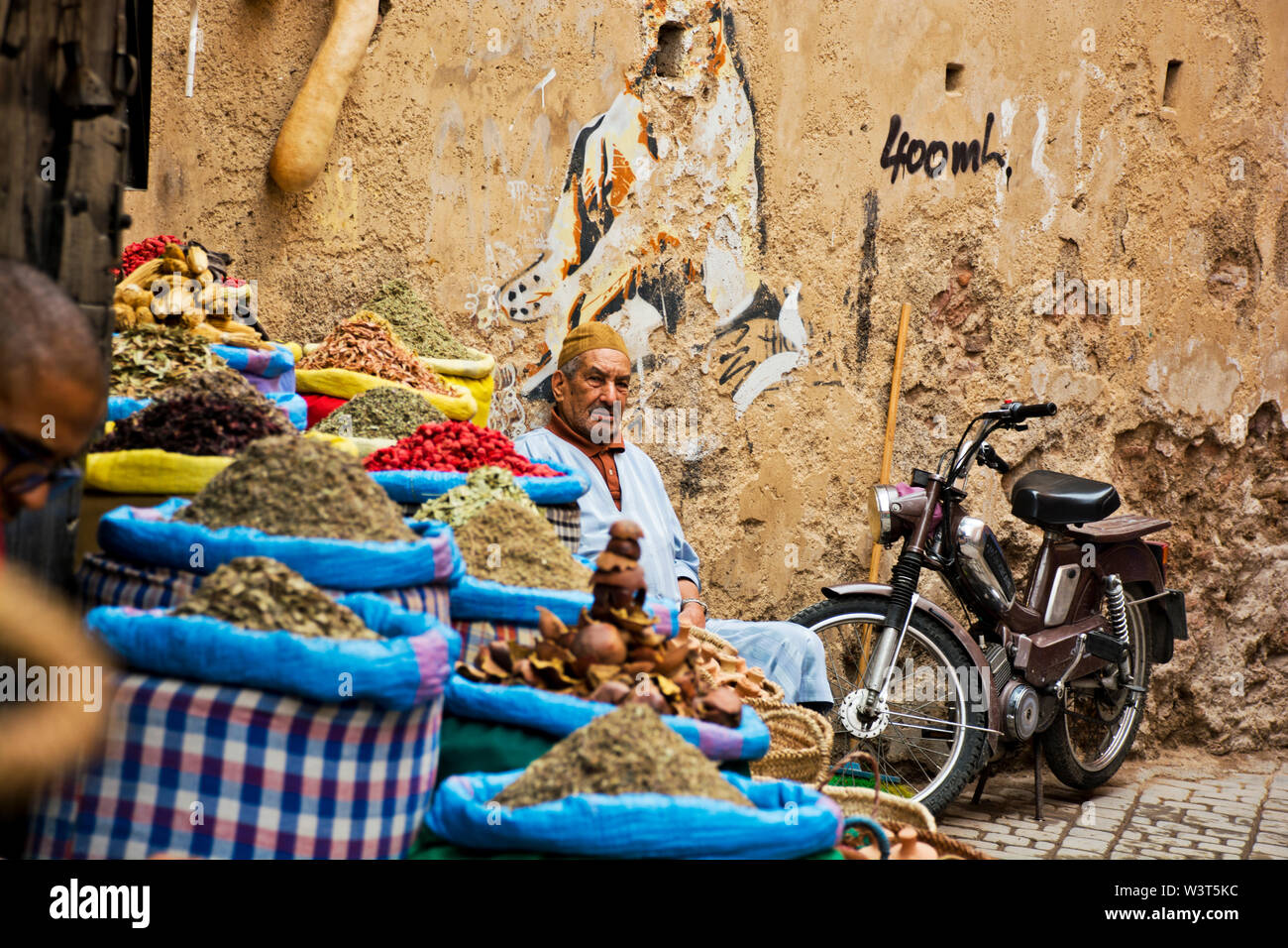 Local Moroccan man selling goods in the streets, alleyways of Marrakech going about daily arabic life in the weathered cultural Medina Stock Photo