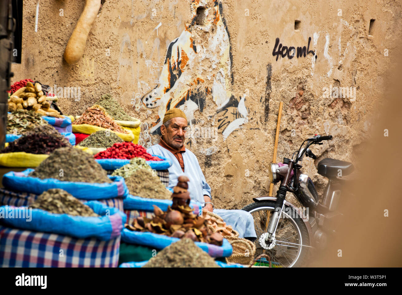 Local Moroccan man selling goods in the streets, alleyways of Marrakech going about daily arabic life in the weathered cultural Medina Stock Photo