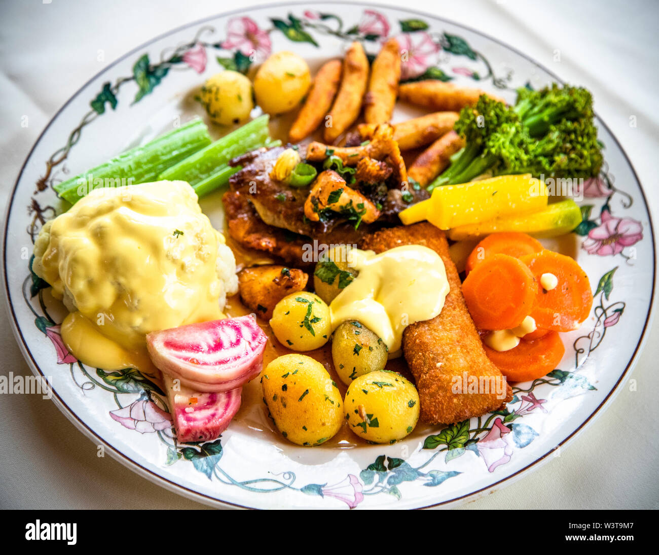 A plate with several potato preparations - including roasted baby potatoes, potato wedges and pan-fried potatoes - plus meat, cauliflower with hollandaise sauce and colourful vegetables is served at the Strixner farm in Ehekirchen, Germany. Every year from September, the farm offers its own potato menu. Stock Photo