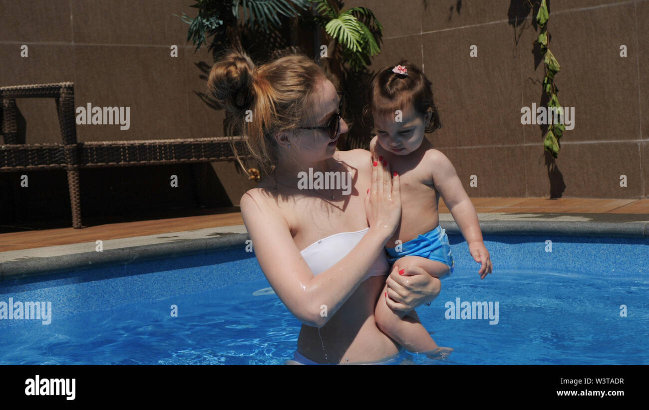 Mom and little daughter are played in the open swimming pool Stock Photo