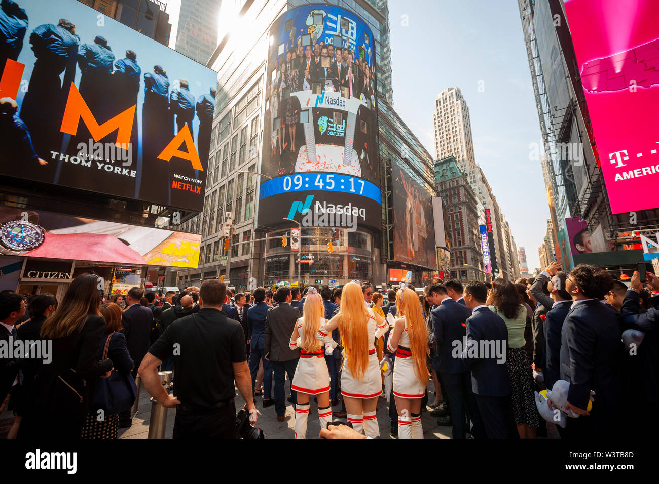 Employees with their families and friends gather at the giant video screen on the Nasdaq stock exchange in Times Square in New York decorated for the debut of the DouYu International Holdings