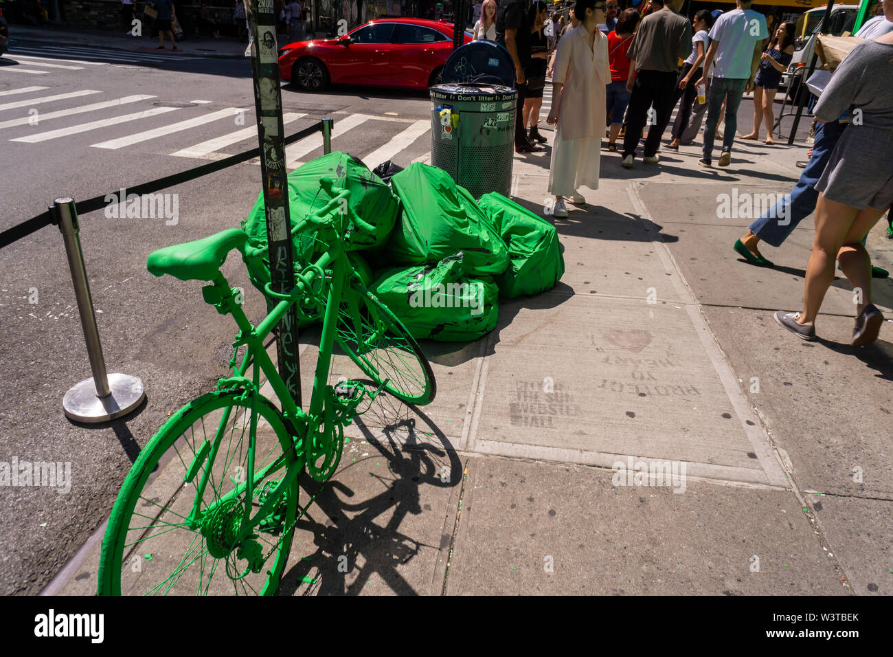 Garbage bags and an “abandoned” bike are painted green outside the