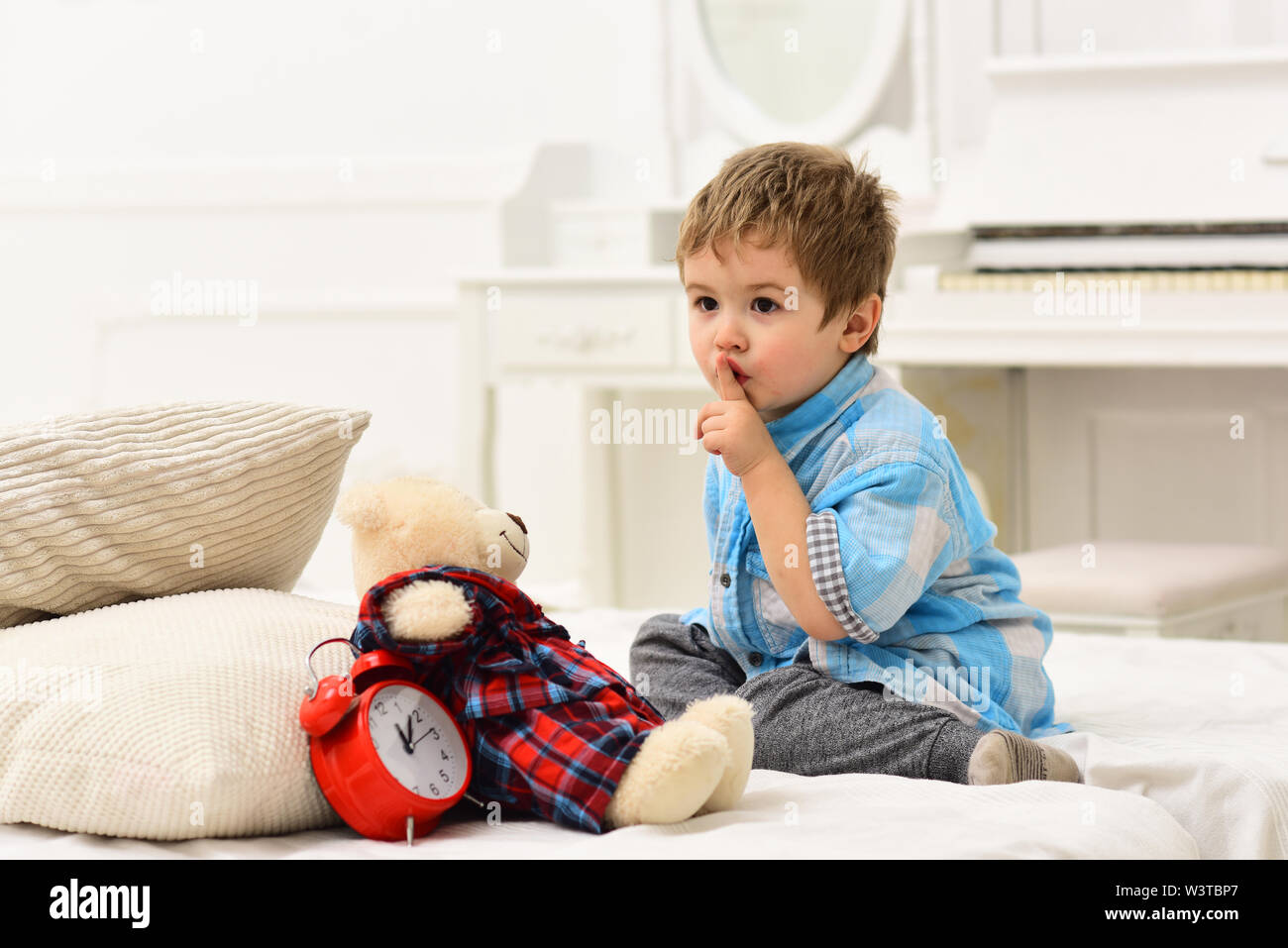 Child in bedroom with silence gesture. Boy with calm face puts